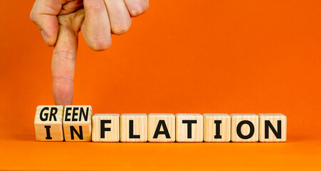 Inflation or greenflation symbol. Concept words Inflation or Greenflation on wooden cubes. Beautiful orange background. Businessman hand. Ecological business inflation greenflation concept. Copy space