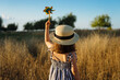 © kaloriya - Little girl holding up a pinwheel toy against clear sky in the meadow