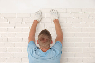 Poster - Professional builder installing new white decorative bricks on wall, back view