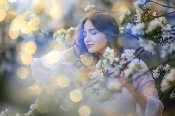 spring portrait of an adult happy woman in a blooming garden, sun rays and glare, april flowers girl