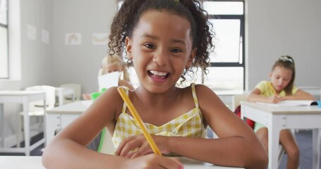 Wall Mural - video of happy biracial girl sitting at school desk and learning