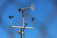 A Wind Monitor Device With Wind Sentry Anemometer To Measure Wind Speed And Direction, Chain Link Fence Shadow On The Background.