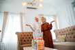 © Odua Images - two smiling veiled Muslim women with hand gestures presenting something stand in the background of the living room