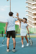 © Odua Images - Double tennis players high-five each other celebrating success while playing on tennis court