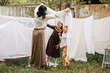 © Yelena Belodedova - a boy and a girl of primary school age help their mother hang freshly laundered laundry on ropes in the spring garden of a country house. the concept of village life, healthy lifestyle