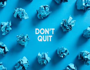 Wall Mural - Do not quit message with crumpled blue paper balls on blue background.