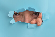 Woman Looking Through A Hole In A Torn Carboard