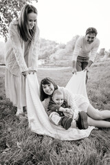 Wall Mural - B&W image of happy family with two children playing on the grass