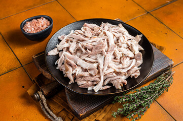 Poster - Shredded chicken meat in a plate. Orange background. Top view