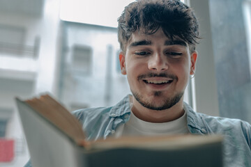 Wall Mural - young man reading a book or studying at home