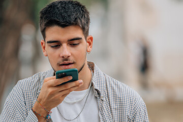 Wall Mural - young man in the street with mobile phone or smartphone sending audio or message