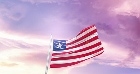 Waving Flag of Liberia in Blue Sky. The symbol of the state on wavy cotton fabric.