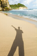 Someone Photographs His Own Shadow During The Day On The Beach Sand In A High Five Handsign Pose.