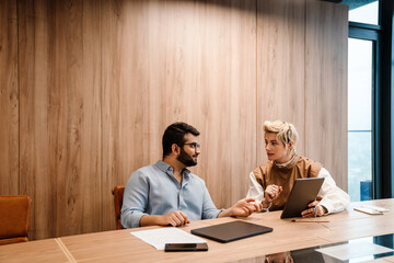 two coworkers discussing business plan while working on laptop together