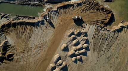 Arial view of open pit sand mine. A front loader loads sand from piles. Heavy mining machinery working in a quarry. lots of wheel tracks and piles of sand like desert dunes or breasts, dry, sandy,sell