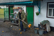 Portrait of positive Ukrainian country man d trying to clean his dirt from rotten pumpkins  with pitchforks the back of homestead