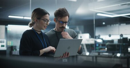 Wall Mural - Portrait of Two Creative Young Female and Male Engineers Using Laptop Computer to Analyze and Discuss How to Proceed with the Artificial Intelligence Software. Standing in High Tech Research Office