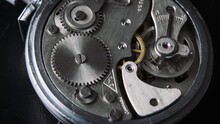 The Mechanism Of Vintage Stopwatch Rotates Close-up. Round Clock Watch Mechanism Working In A Macro. Old Retro Clockwork Gears, Cogwheels, And Pendulum Movement Inside The Ancient Clock. 4K