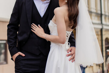 Wall Mural - the groom and the bride in a wedding dress stand together on the street