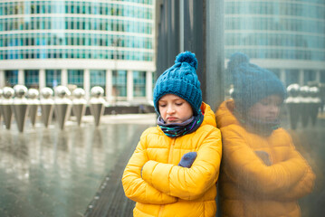 a disgruntled sad boy stands with his arms crossed in the center of the metropolis