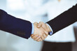 © rogerphoto - Business people shaking hands at meeting or negotiation, close-up. Group of unknown businessmen and a woman standing in a modern office. Teamwork, partnership and handshake concept.