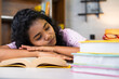 © WESTOCK - Tired young indian student sleeping on table during reading for examination at home - concept of overworked, knowledge and exam problem