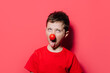 © ADDICTIVE STOCK - Humorous boy in casual red shirt with red poky nose posture in studio photo