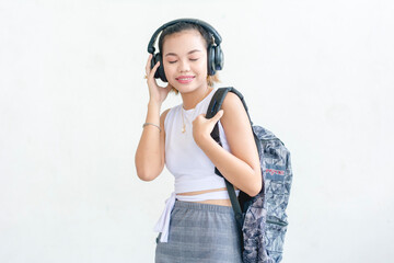 Wall Mural - A short haired student wearing a white sleeveless top and printed skirt listening intently to music isolated on a white background