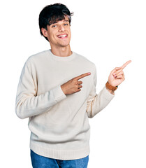 Canvas Print - Handsome hipster young man wearing casual winter sweater smiling and looking at the camera pointing with two hands and fingers to the side.