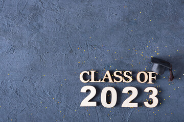 Class of 2023 concept. Wooden number 2023 with graduated cap on cement background