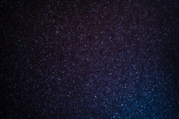 Wall Mural - Organic dust particles floating on a colorful light beam on black background. Glittering sparkling flickering overlay. High quality photo
