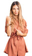 © Krakenimages.com - Beautiful caucasian woman with blonde hair wearing summer jumpsuit in hurry pointing to watch time, impatience, looking at the camera with relaxed expression