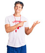 © Krakenimages.com - Young handsome man wearing lifeguard t shirt and whistle amazed and smiling to the camera while presenting with hand and pointing with finger.