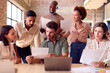 © Monkey Business - Multi-Cultural Business Team Meeting Around Laptop In Busy Office