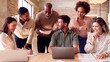 © Monkey Business - Multi-Cultural Business Team Meeting Around Laptop In Busy Office