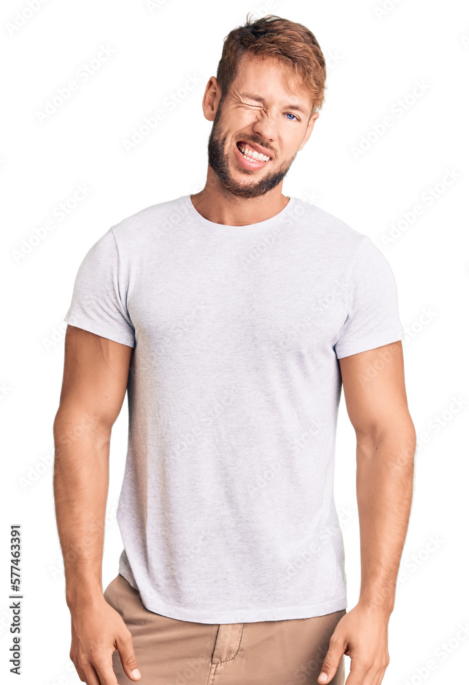 Young caucasian man wearing casual white tshirt winking looking at the camera with sexy expression, cheerful and happy face.