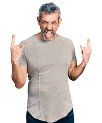 Sticker - Middle age hispanic with grey hair wearing casual grey t shirt shouting with crazy expression doing rock symbol with hands up. music star. heavy concept.