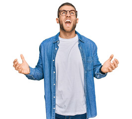 Canvas Print - Young caucasian man wearing casual clothes crazy and mad shouting and yelling with aggressive expression and arms raised. frustration concept.