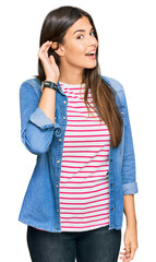 Canvas Print - Young brunette woman wearing casual clothes smiling with hand over ear listening an hearing to rumor or gossip. deafness concept.