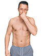 © Krakenimages.com - Handsome young man wearing swimwear shirtless smelling something stinky and disgusting, intolerable smell, holding breath with fingers on nose. bad smell