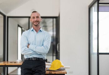 Wall Mural - Portrait, Successful and confident Caucasian male engineer or architect stands with arms crossed in the engineer's office.