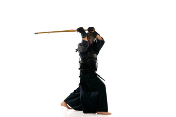 Wall Mural - Portrait of man, professional kendo athlete in uniform posing, training with shinai sword against white studio background. Concept of martial arts, sport, Japanese culture, action and motion