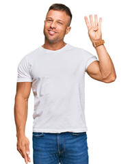 Handsome muscle man wearing casual white tshirt showing and pointing up with fingers number four while smiling confident and happy.