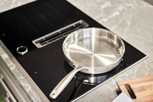 New cookware set on black induction hob in modern kitchen. Pot and frying pan in the kitchen on the hob. cooking concept - close up of kitchen table with modern equipment