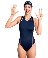 Wall Mural - Young beautiful hispanic woman wearing swimwear and swimmer glasses showing and pointing up with fingers number eight while smiling confident and happy.