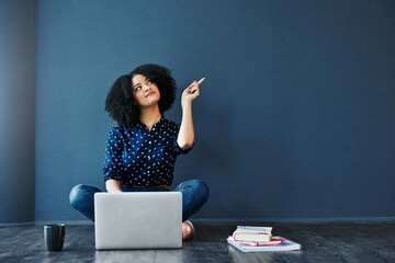 Poster - Act on your dreams. Studio shot of an attractive young woman looking thoughtful while using a laptop against a blue background.