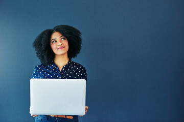 Poster - Social media never fails to tickle the mind. Studio shot of an attractive young woman looking thoughtful while using a laptop against a blue background.