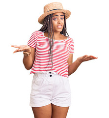 Canvas Print - Young african american woman with braids wearing summer hat clueless and confused with open arms, no idea concept.