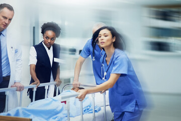 Aufkleber - Rushing to the ER. Shot of a group of medical professionals rushing a patient on a gurney down a hospital corridor.
