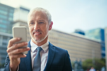 Aufkleber - Letting his fingers do the talking. Shot of a confident businessman using his cellphone while standing outside his office building.